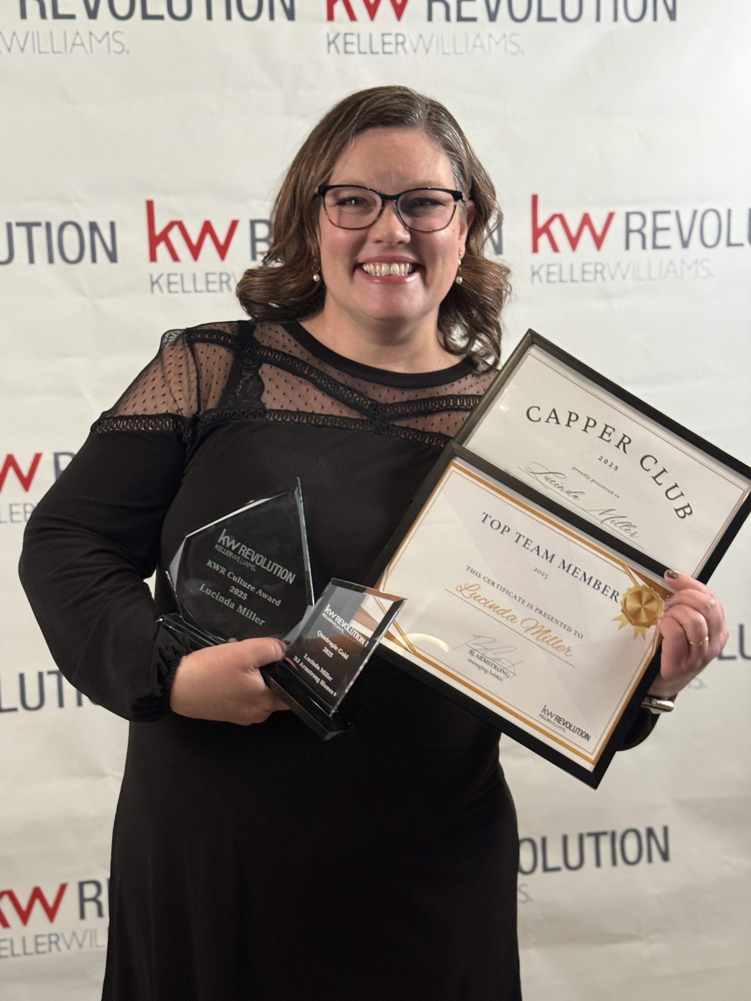 Lucinda Miller holding her 2025 awards at the KW Revolution banner